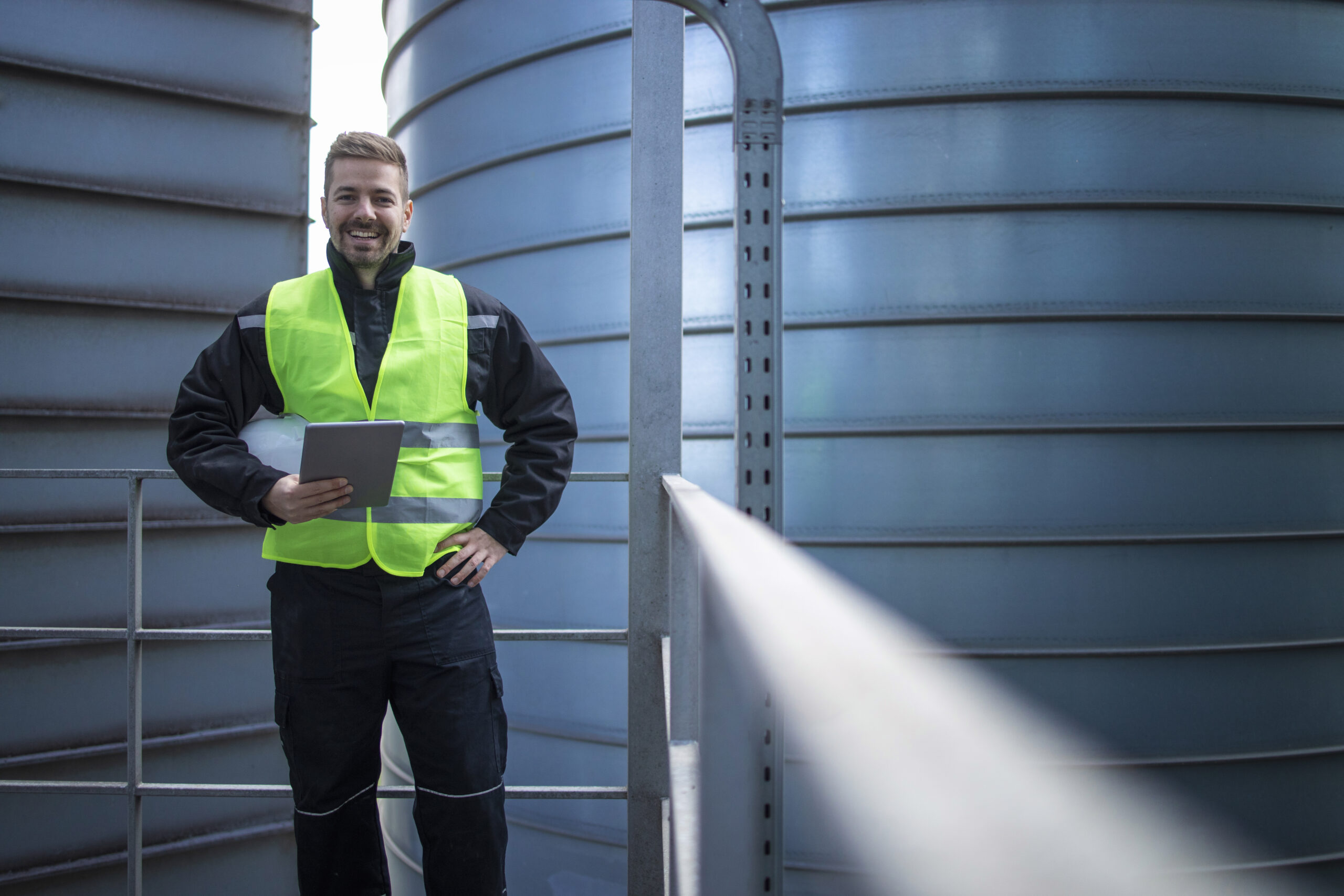 portrait factory engineer worker standing metal platform industrial storage tanks looking camera scaled