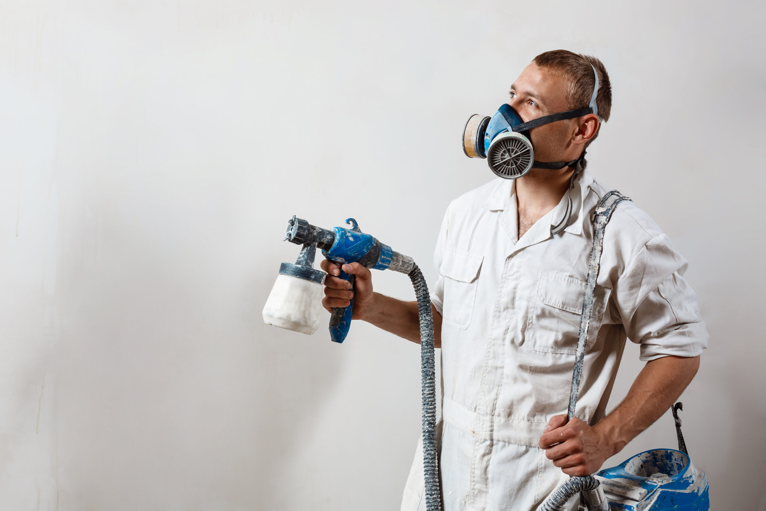 worker painting wall with spray gun white color scaled